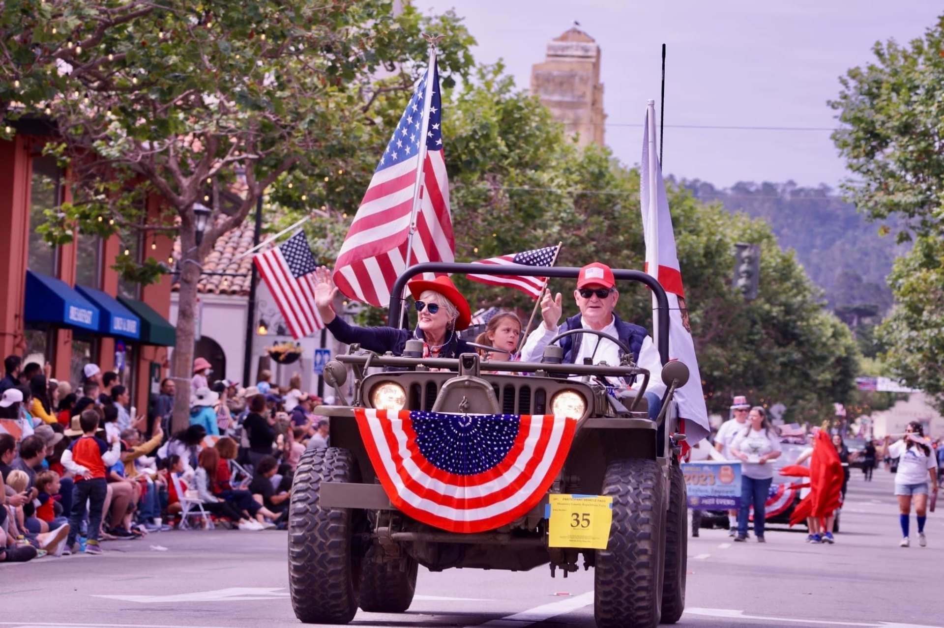 Vicki Nohrden waving from a flag-draped jeep in the Monterey County parade